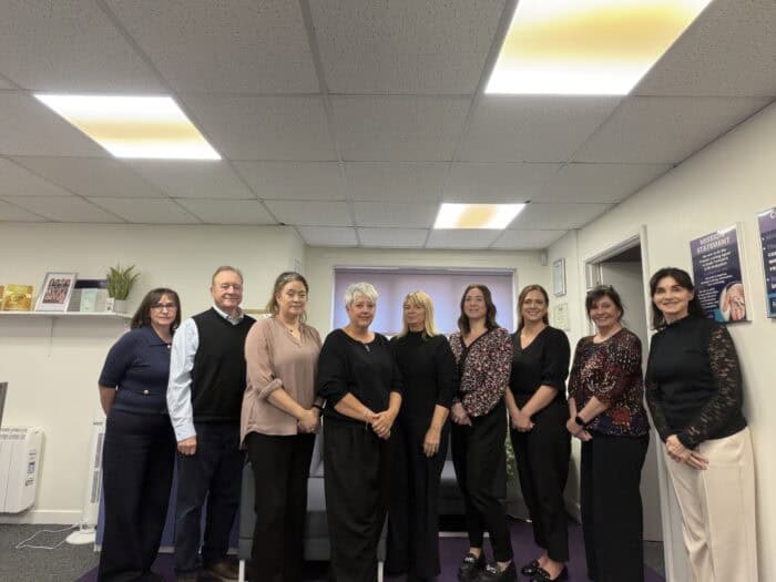 Team photo of nine staff members standing together inside an office